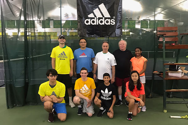 Tennis campers and coaches pose for a group photo during an adidas Tennis Camp.